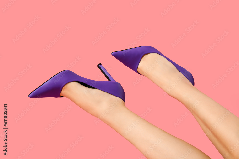 Female legs in stylish high heels on pink background, closeup