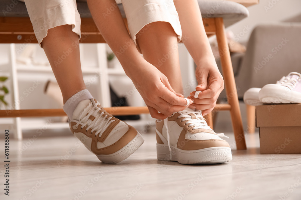 Woman in stylish sneakers tying shoe lace, closeup