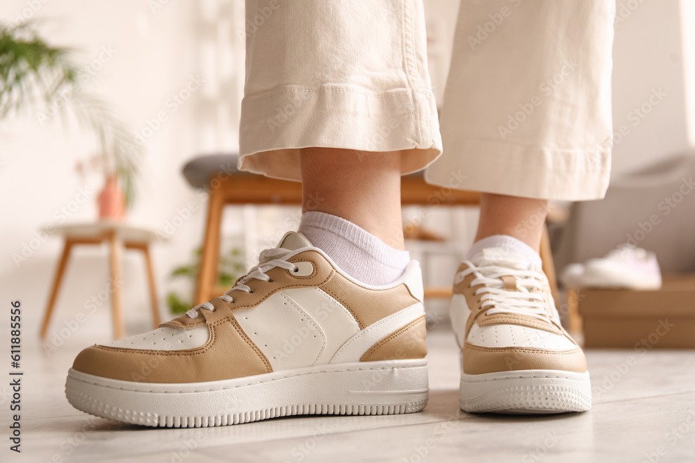 Woman trying on stylish sneakers in boutique, closeup