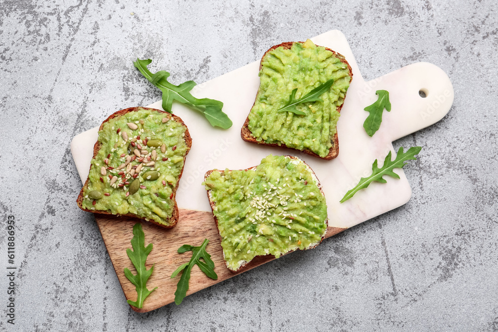 Board of tasty avocado toasts on light background