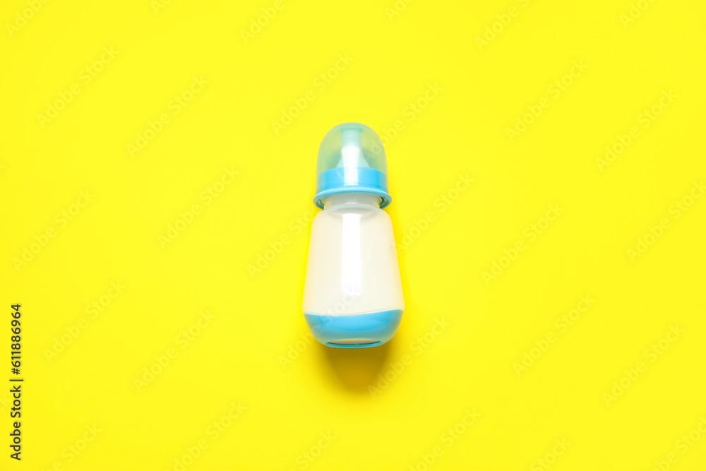 Bottle with milk for baby on yellow background