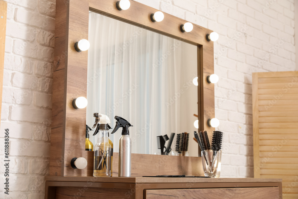 Different hairdressing tools on table near light brick wall in salon