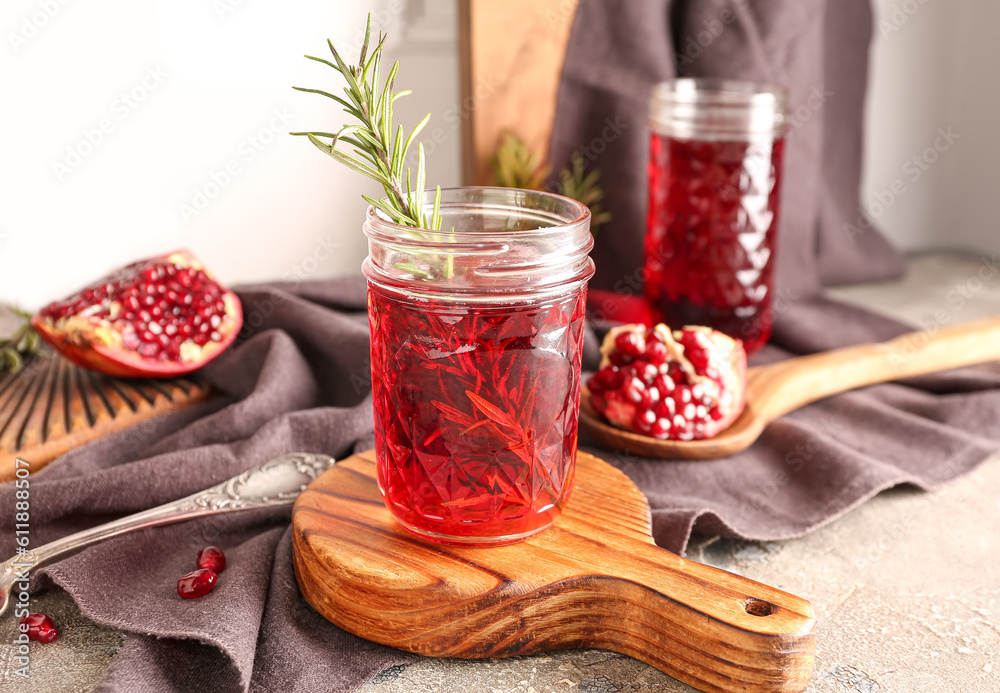 Spoon with fresh pomegranate and glasses of juice on grey table