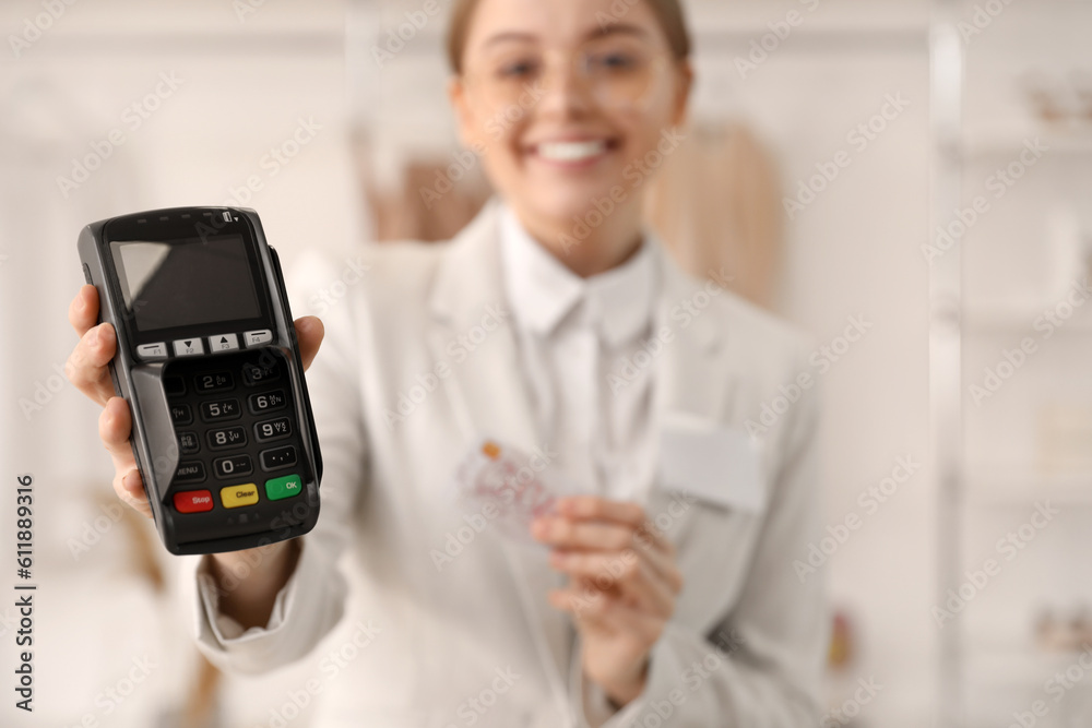 Female seller with payment terminal and gift card in boutique, closeup