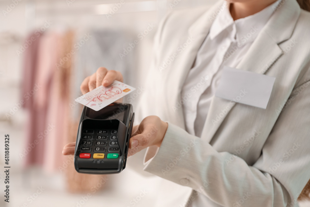 Female seller with payment terminal and gift card in boutique, closeup