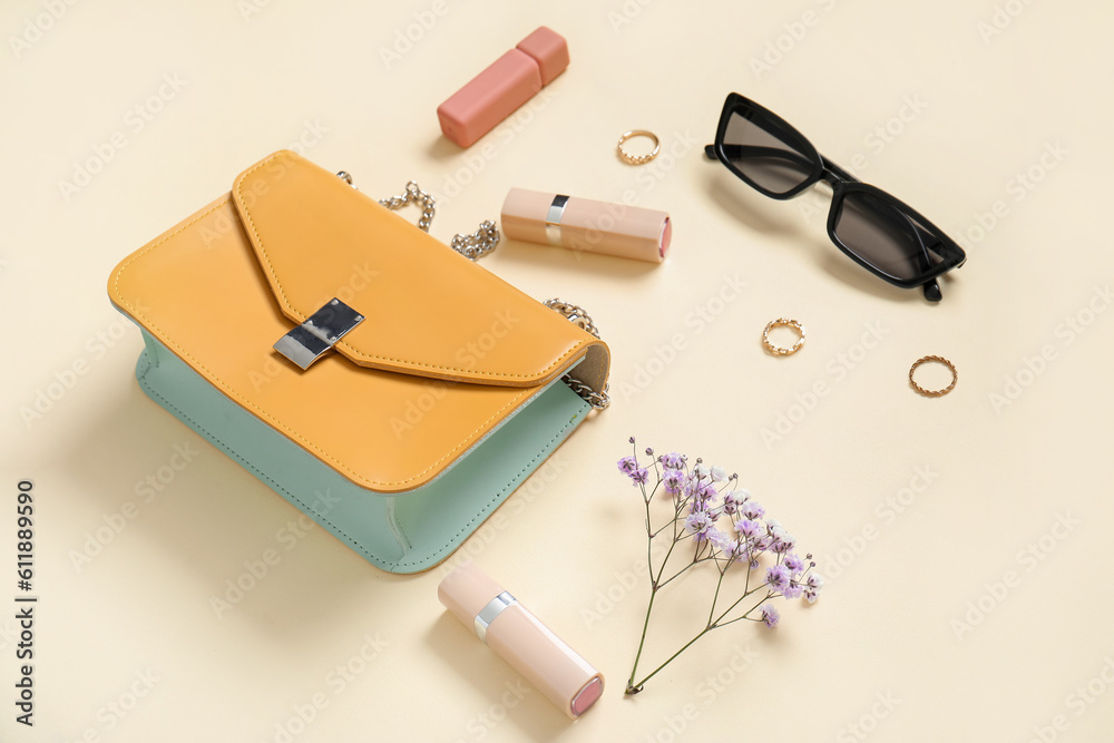 Sunglasses, purse, lipsticks, gypsophila flowers and jewellery on yellow background