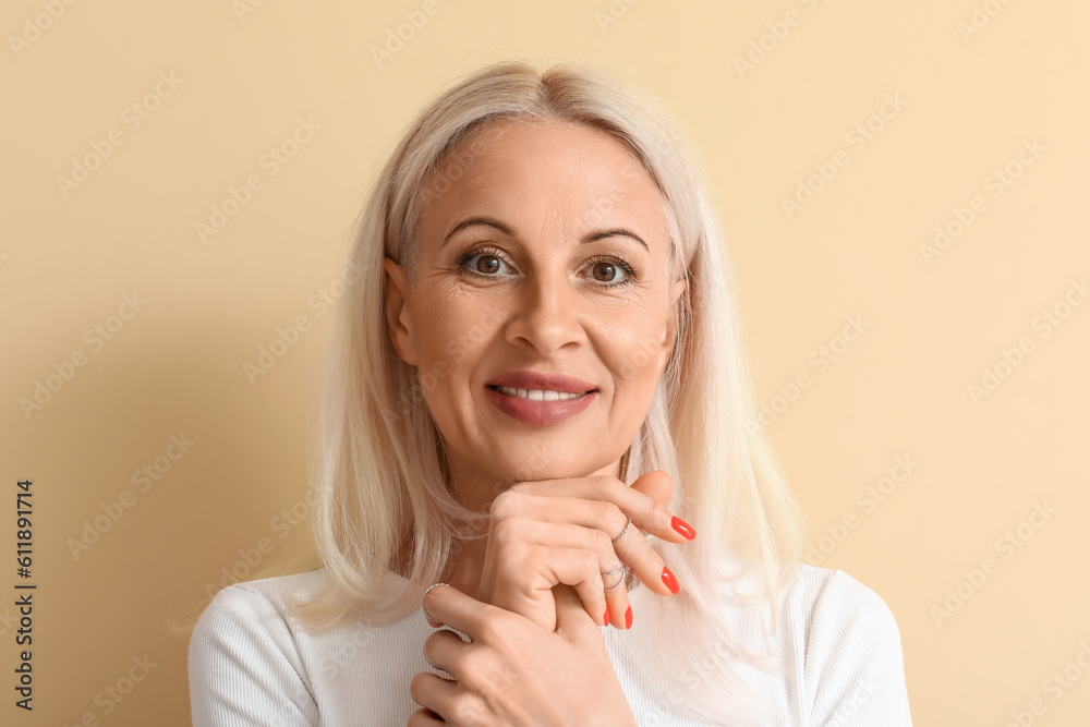 Mature blonde woman on beige background, closeup