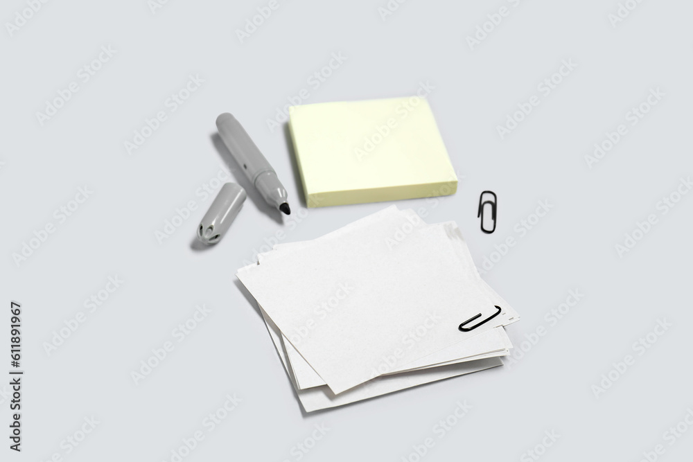 Sticky notes with paperclips and marker on grey background