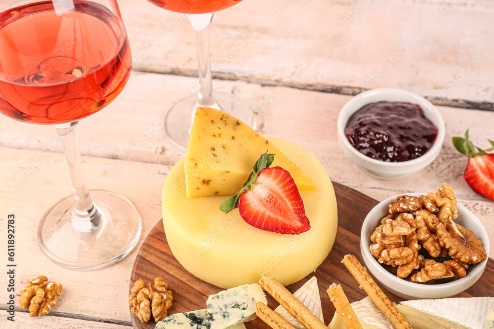 Board with different tasty cheese on light wooden background