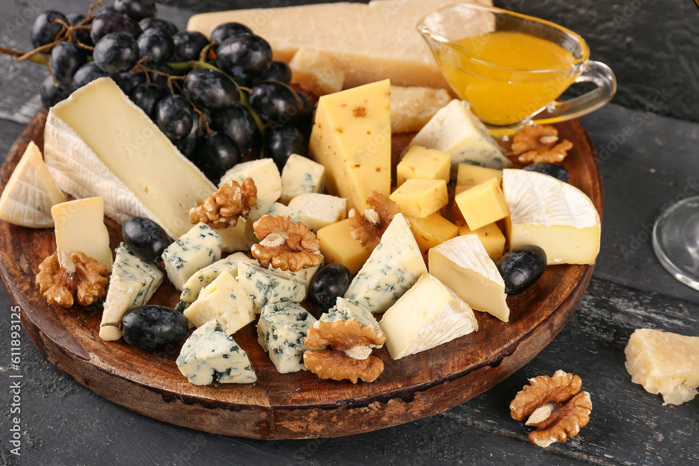 Plate with pieces of tasty cheese on dark wooden background