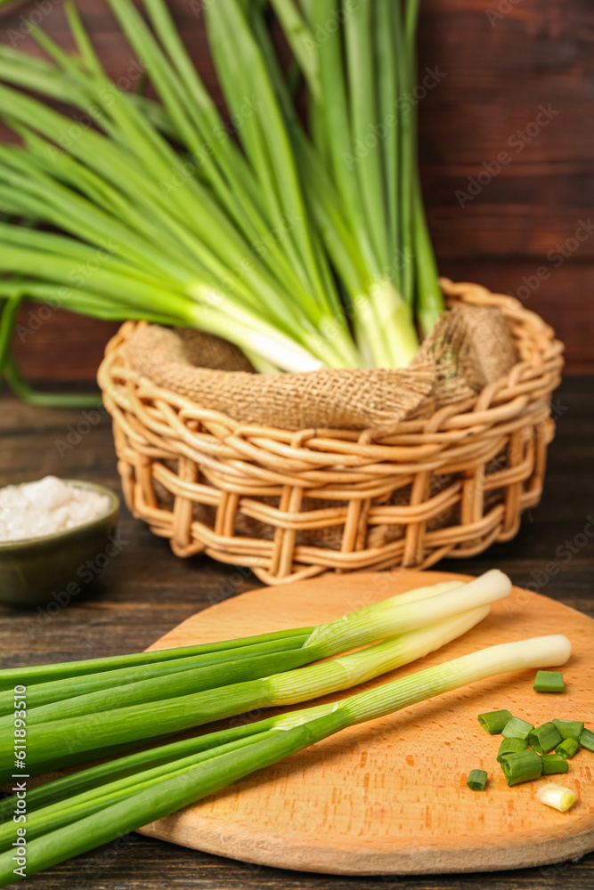 Board with fresh green onion on wooden background