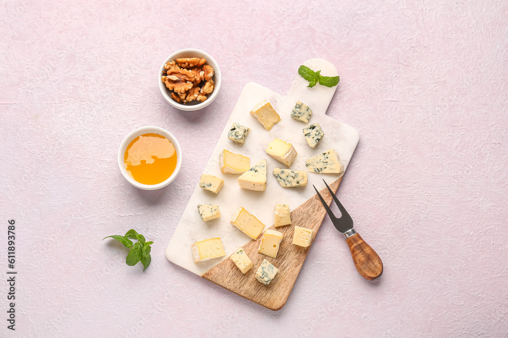 Board with pieces of tasty cheese, nuts and honey on light background