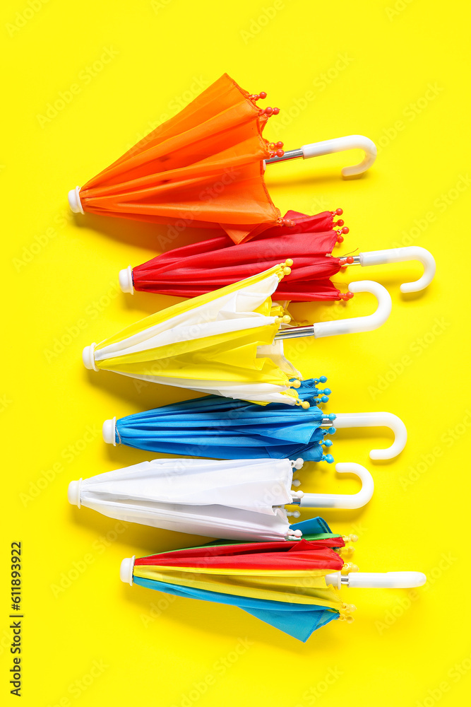 Different mini umbrellas on yellow background