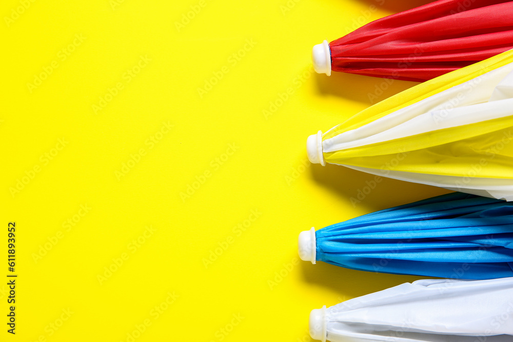 Different mini umbrellas on yellow background