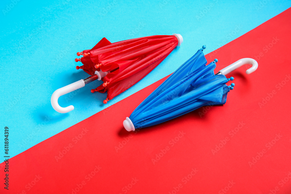 Red and blue mini umbrellas on color background