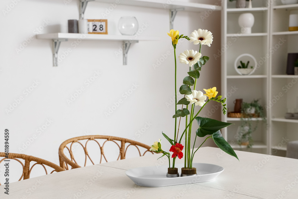 Beautiful ikebana on dining table in room