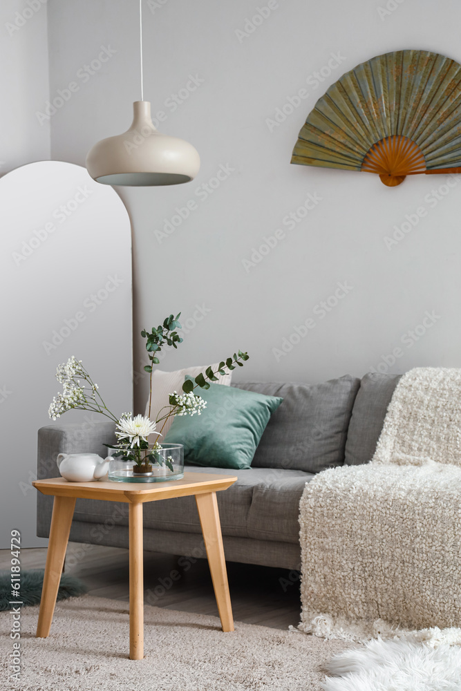 Interior of living room with ikebana on table and sofa