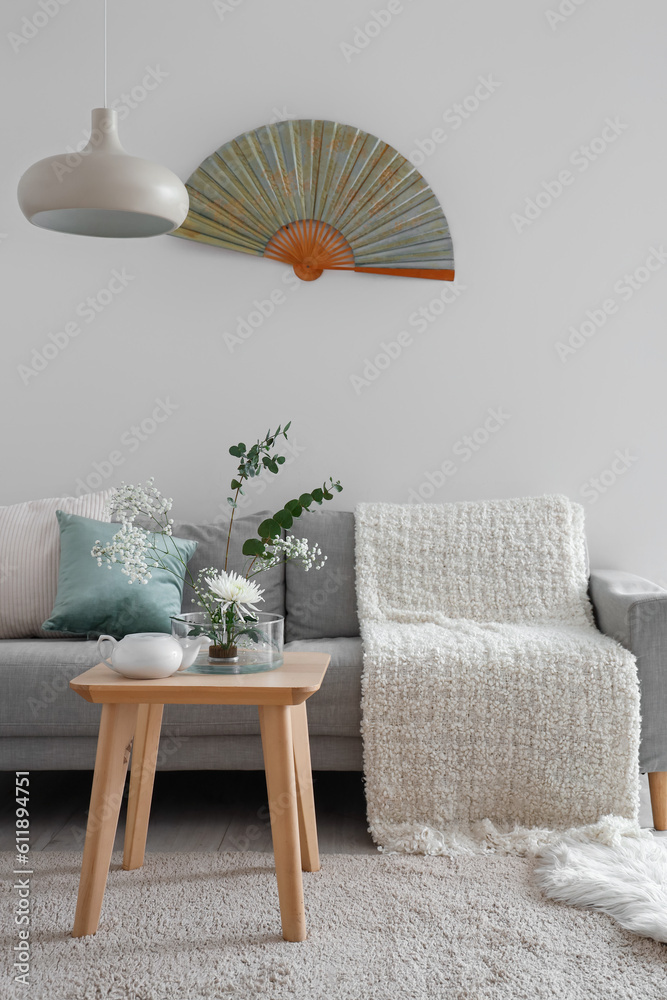 Beautiful ikebana with teapot on table in living room