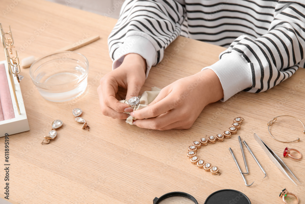 Woman cleaning beautiful jewelry at wooden table, closeup