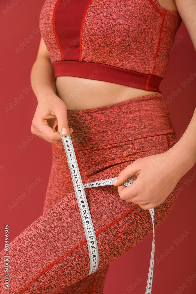 Young woman with measuring tape on burgundy background. Diet concept