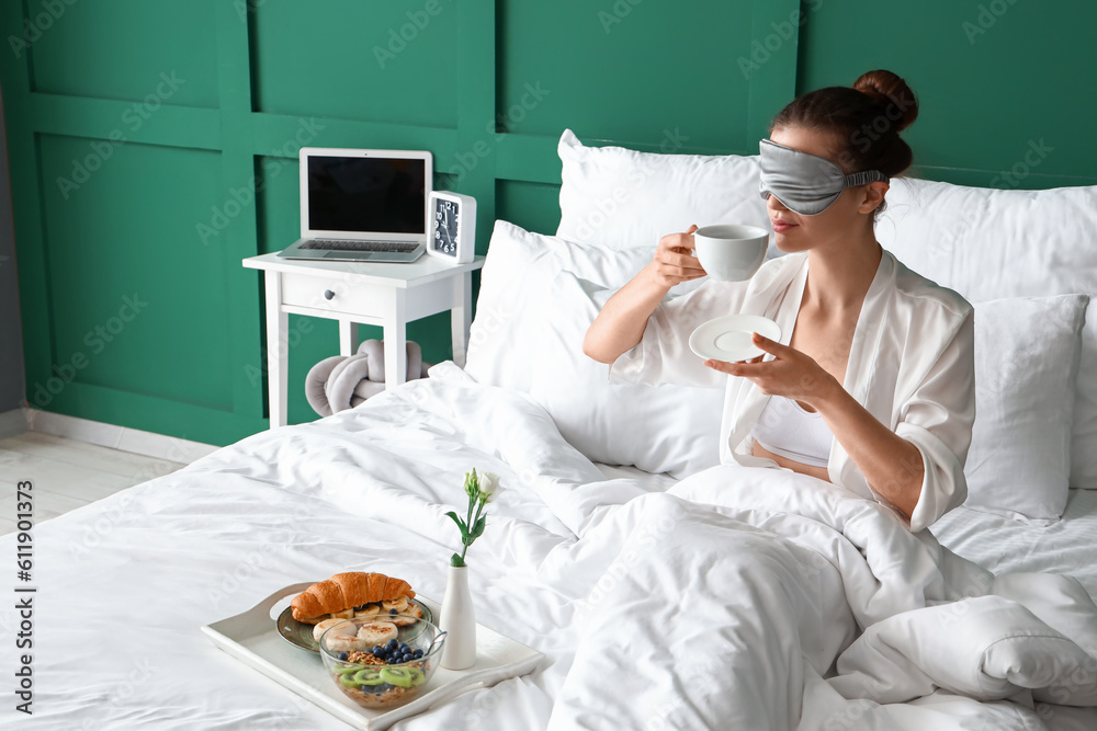 Morning of young woman with cup of coffee in bedroom