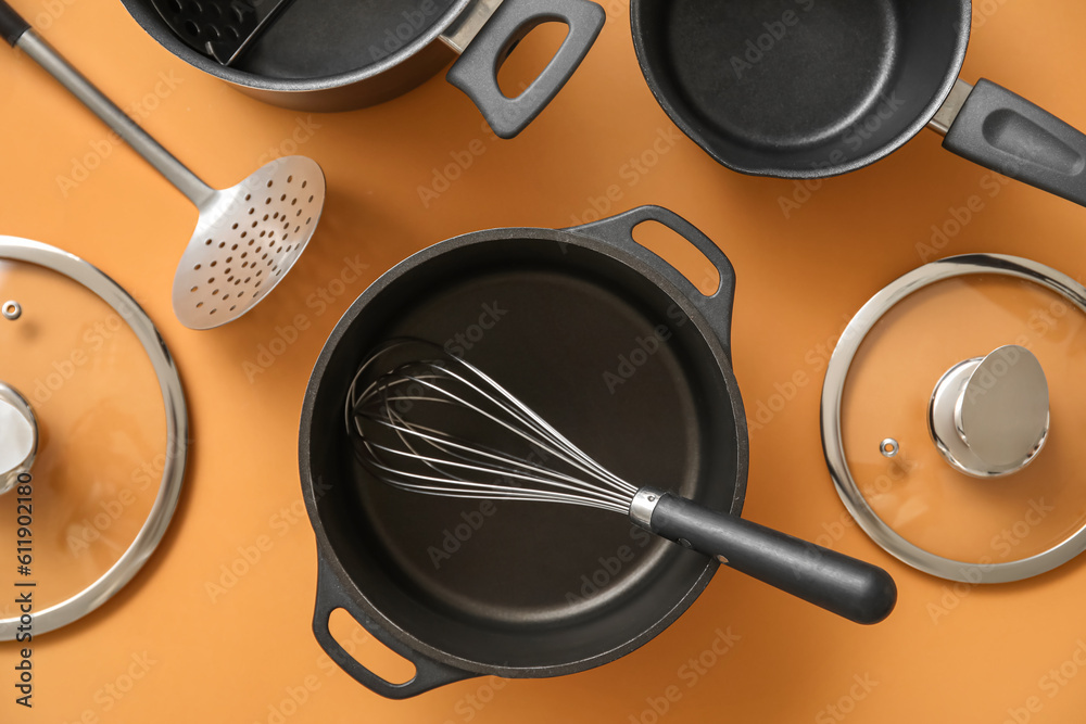 Set of different kitchen utensils on orange background