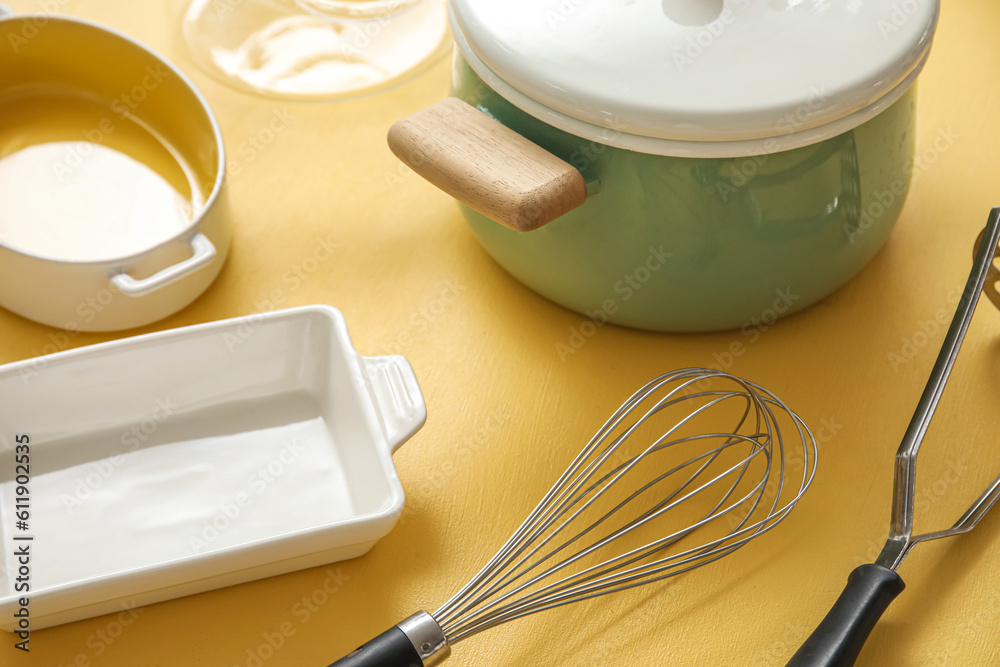 Set of different kitchen utensils on beige background, closeup