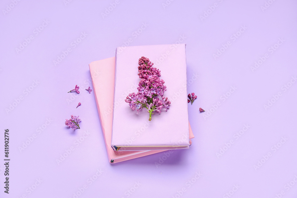 Lilac twig on notebooks on color background