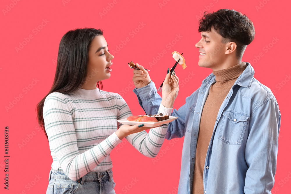 Young couple eating sushi on red background