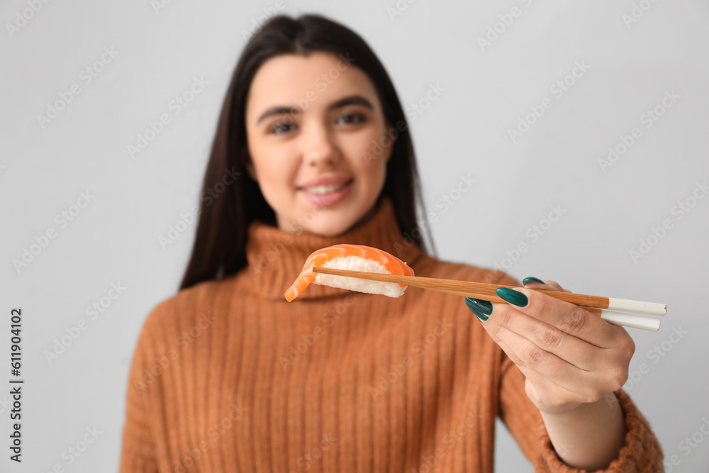 Young woman with sushi on light background, closeup