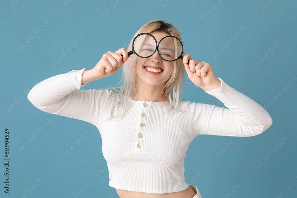 Young woman with magnifiers on blue background