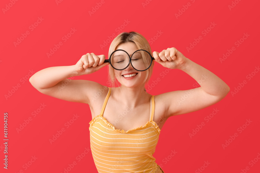 Young woman with magnifiers on red background