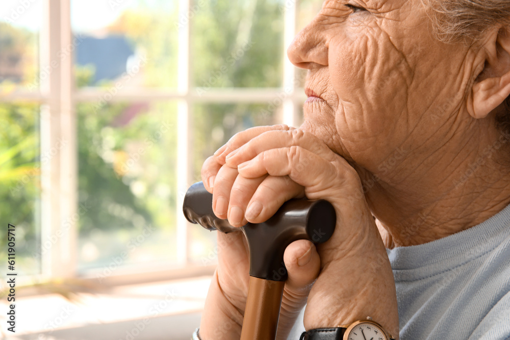 Senior woman with walking stick at home, closeup