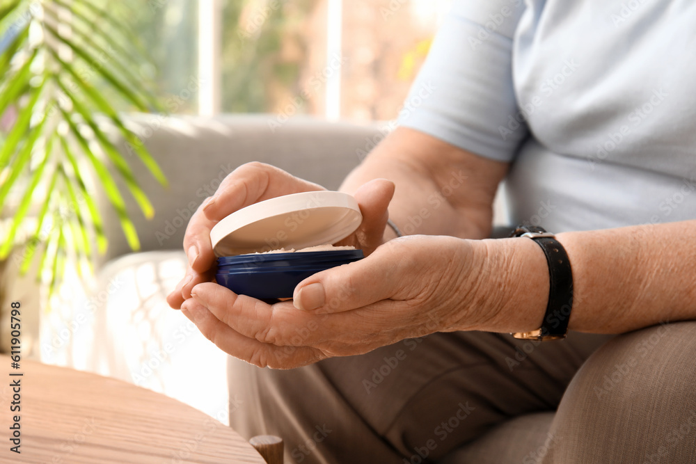 Senior woman with jar of cream at home, closeup