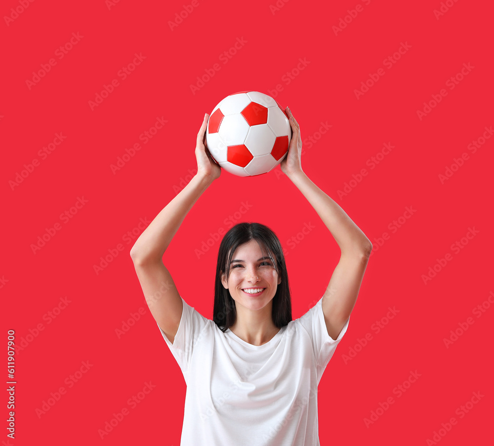 Happy young woman with soccer ball on red background