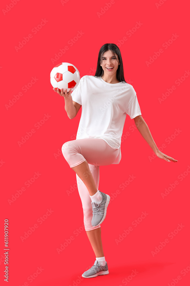 Happy young woman with soccer ball on red background