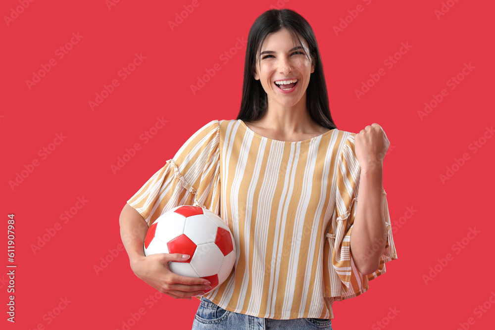 Happy young woman with soccer ball on red background