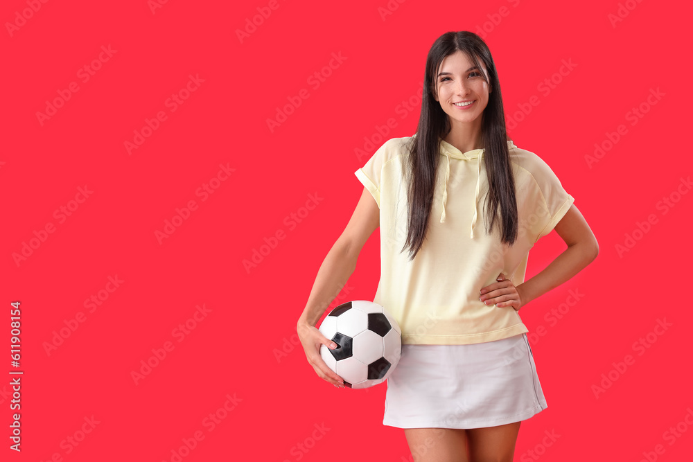 Young woman with soccer ball on red background