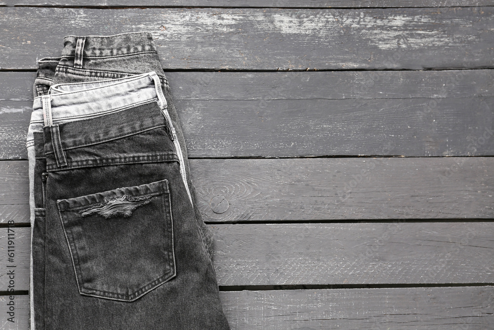 Different stylish denim jeans on grey wooden background