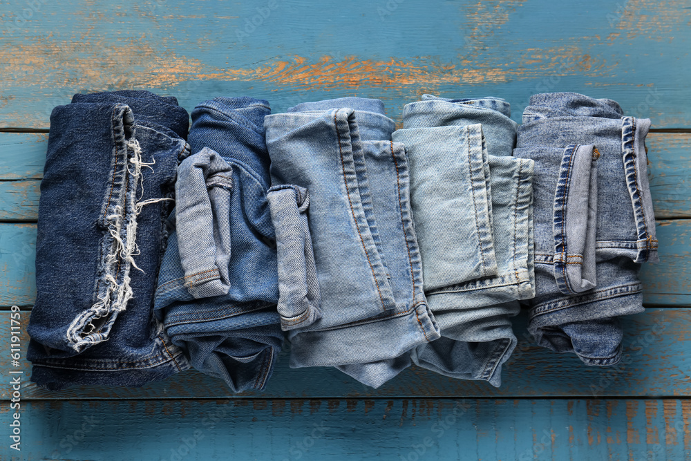 Different rolled jeans on blue wooden background