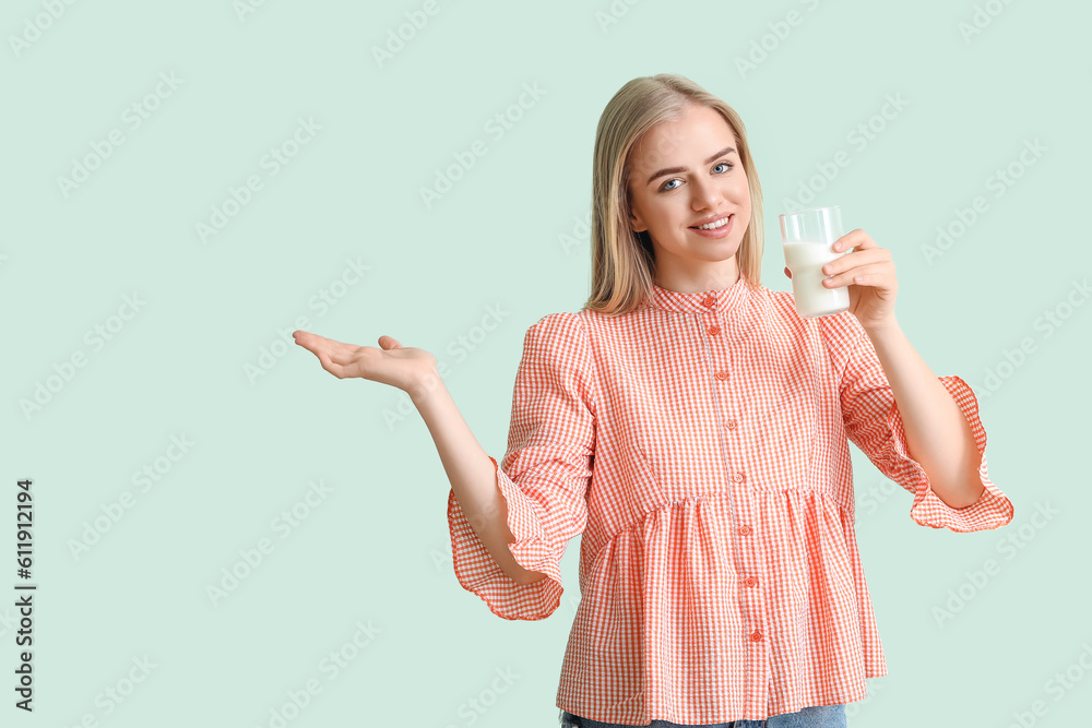 Beautiful young woman with glass of milk on mint background