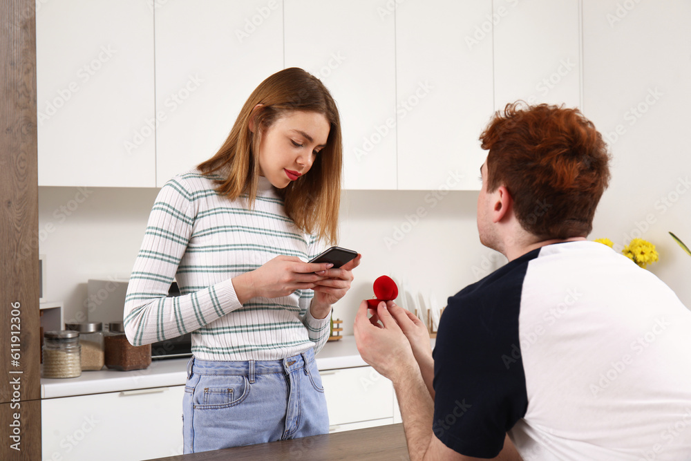 Young woman with mobile phone get proposed in kitchen