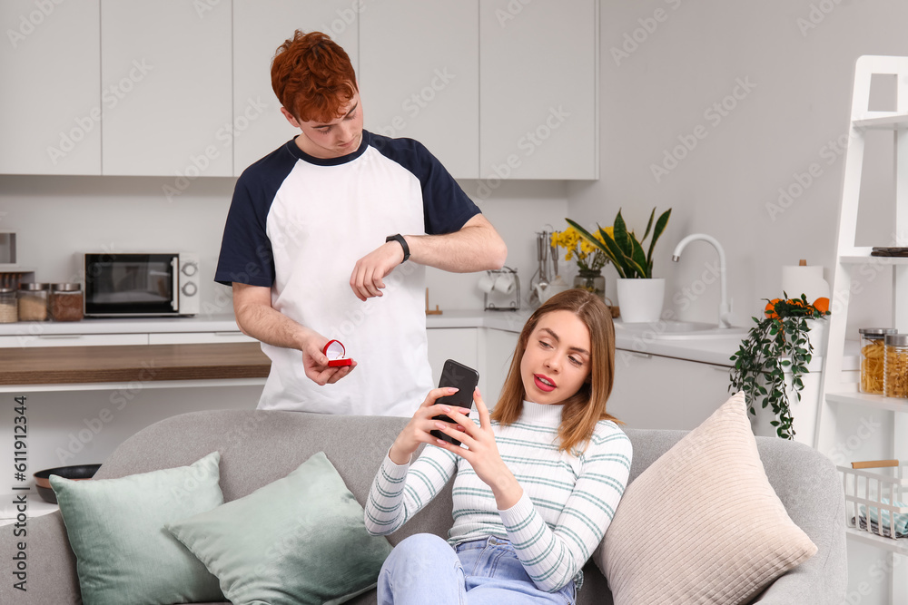 Waiting young man proposing to his girlfriend with mobile phone in kitchen