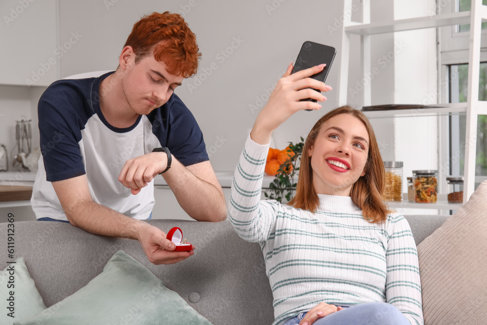 Waiting young man proposing to his girlfriend with mobile phone in kitchen