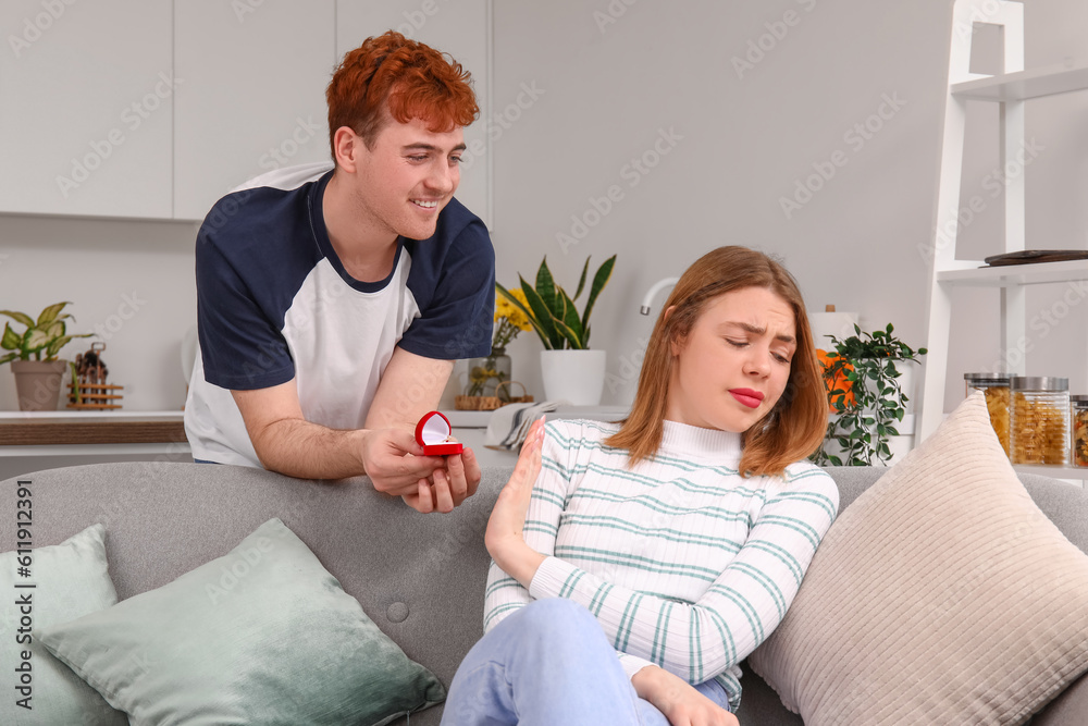 Young woman rejecting marriage proposal from her boyfriend in kitchen