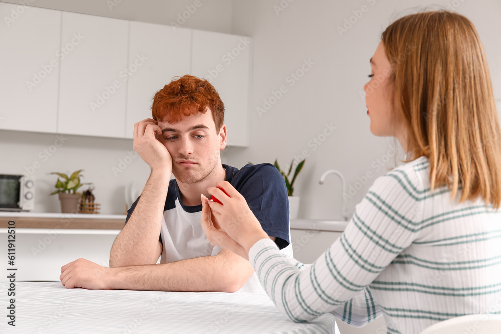 Young woman proposing to her upset boyfriend in kitchen