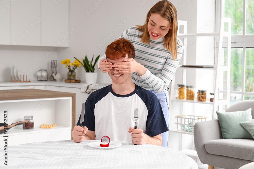 Young woman proposing to her boyfriend at table in kitchen