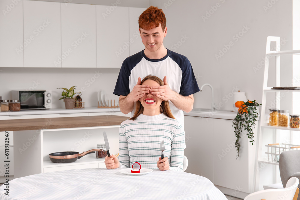 Young man proposing to his girlfriend in kitchen