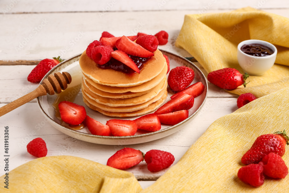 Plate with sweet pancakes and berries on light wooden background, closeup