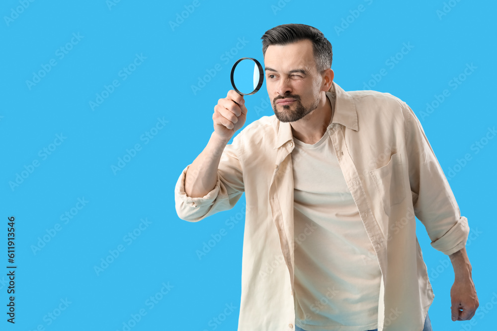 Handsome man with magnifier on blue background